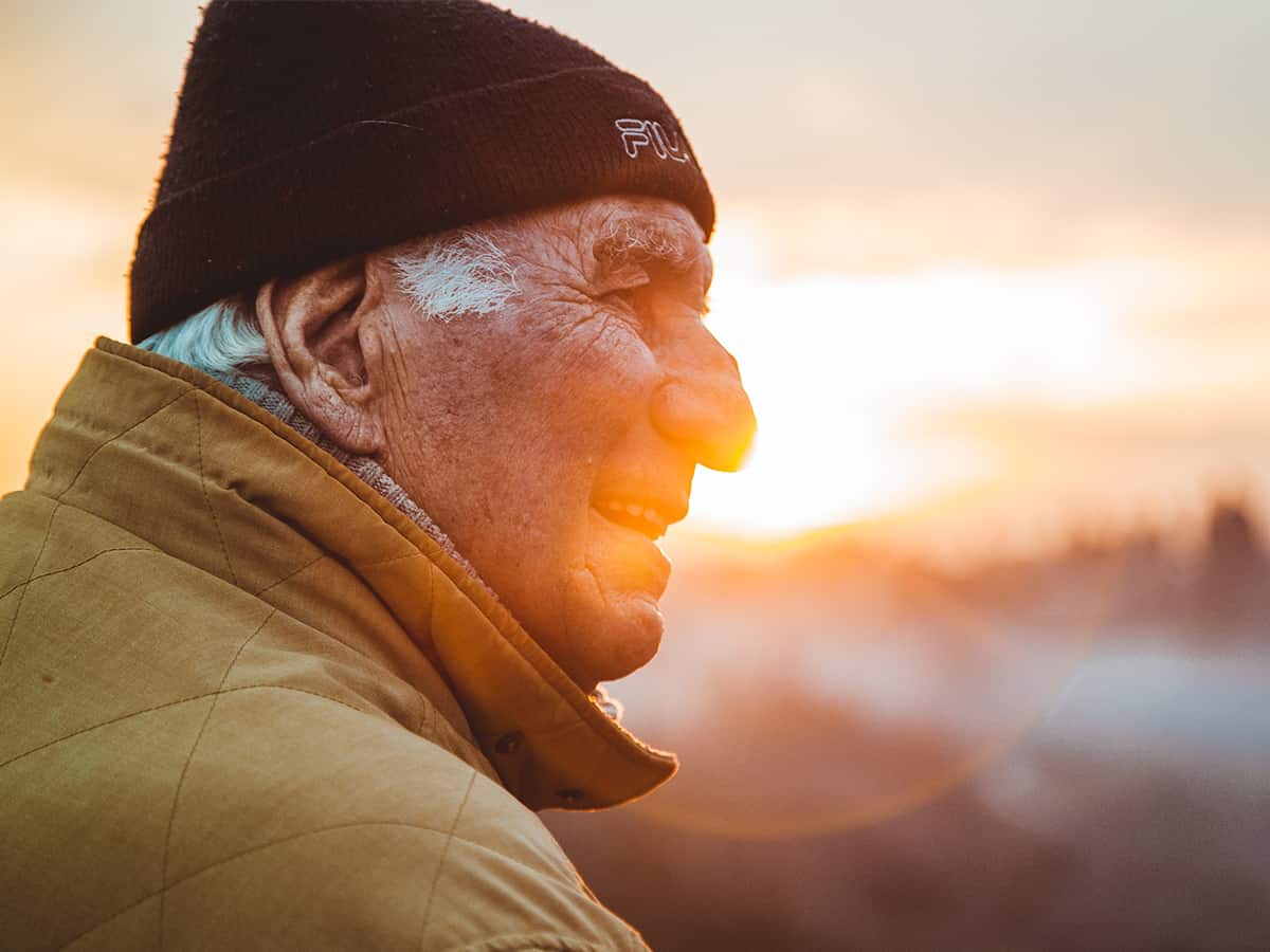 An elderly man watching the sunset.