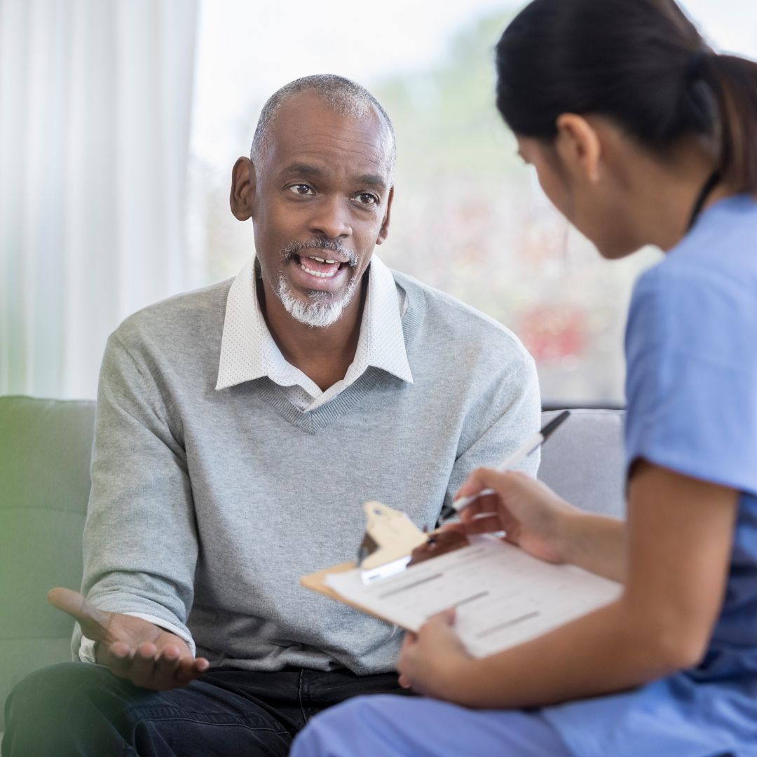 Man speaking with nurse who is holding a clipboard 