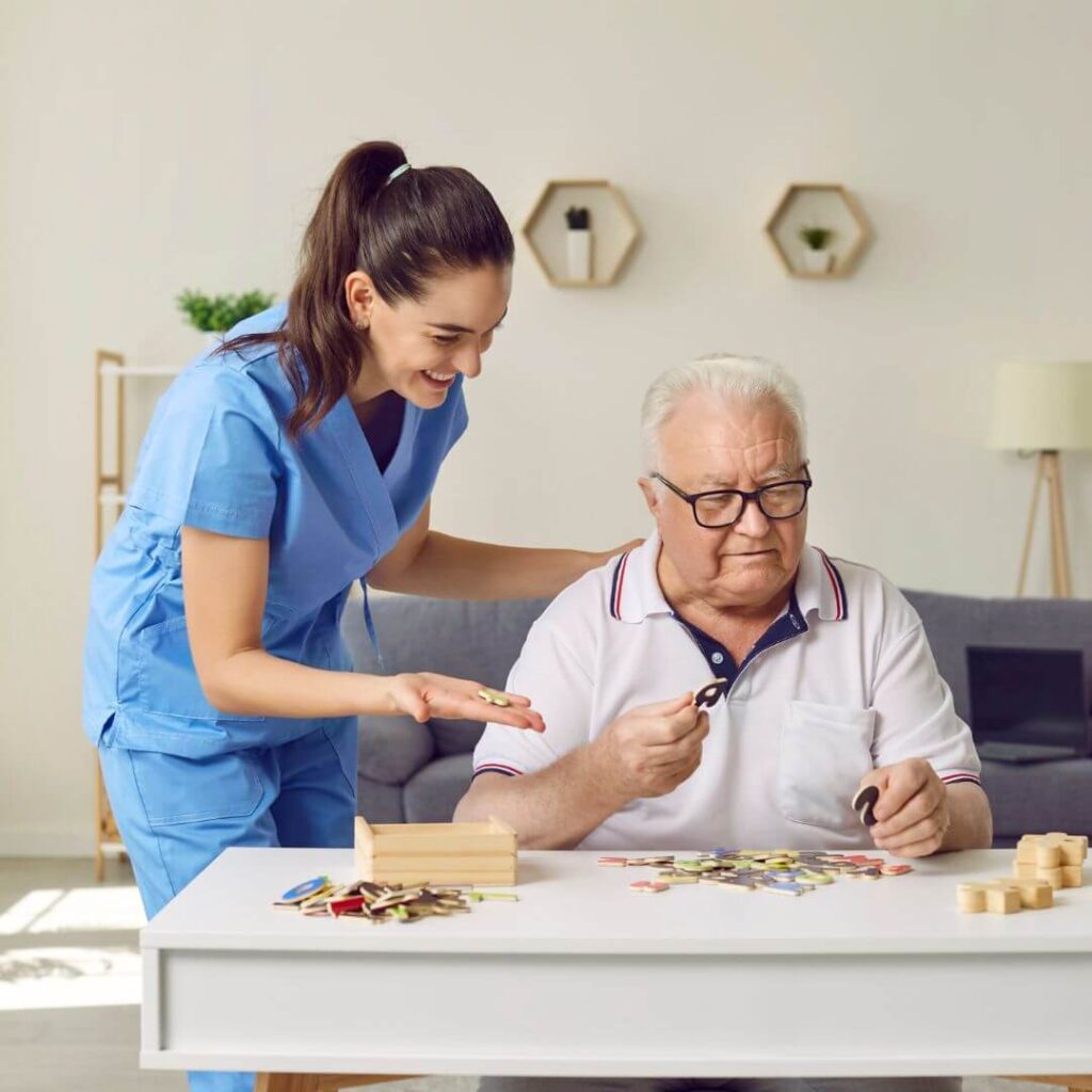 an older gentleman working on a puzzle with assistance